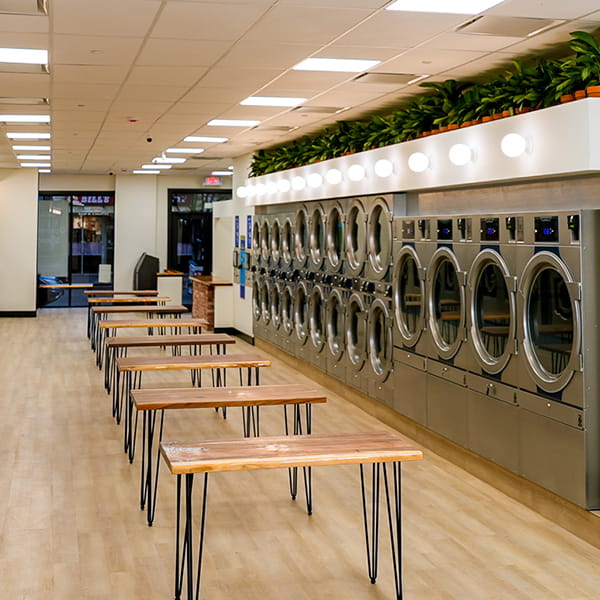 Row of brand-new commercial washers and dryers at Legacy Laundry